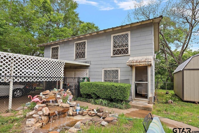 back of property featuring a shed, fence, and an outbuilding