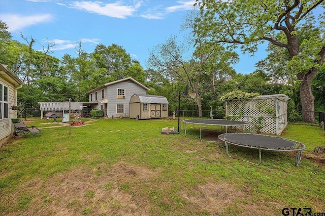 view of yard featuring a storage shed, a trampoline, a fenced backyard, and an outbuilding