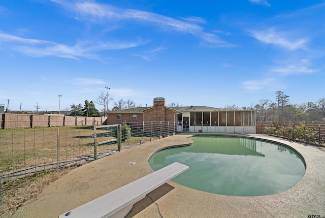 view of swimming pool featuring a diving board and a sunroom