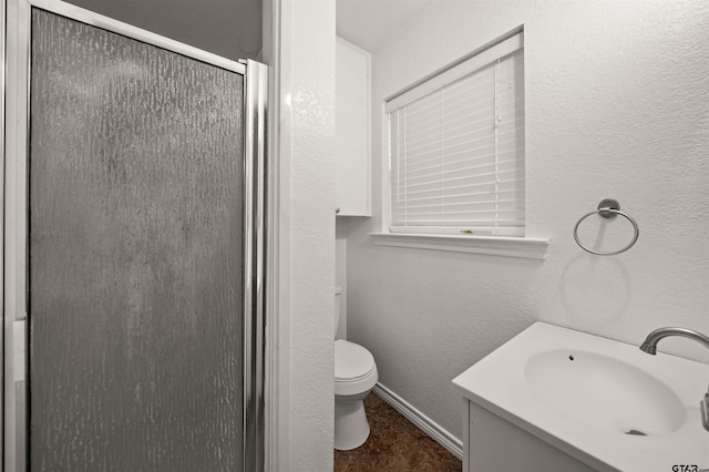 bathroom featuring toilet, a shower with door, and vanity