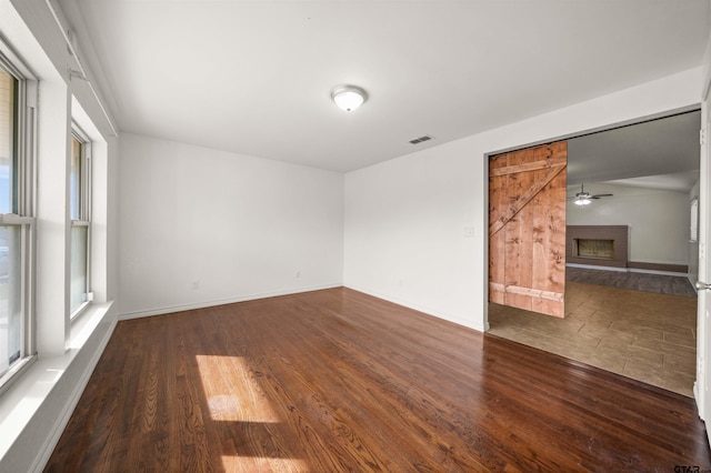 unfurnished room with a healthy amount of sunlight, a barn door, and dark hardwood / wood-style floors