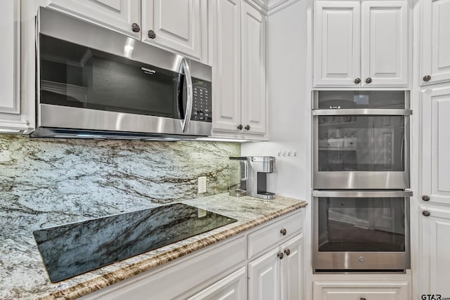 kitchen featuring light stone counters, stainless steel appliances, decorative backsplash, and white cabinetry