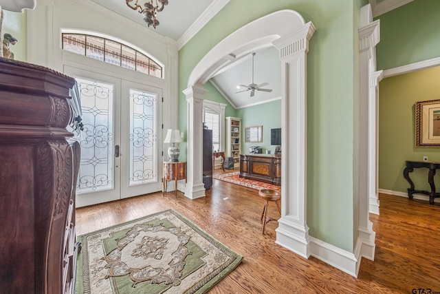 entrance foyer with decorative columns, wood finished floors, arched walkways, and ornamental molding