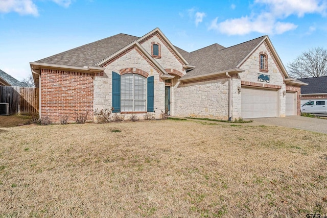 view of front of home featuring a front yard, concrete driveway, stone siding, and roof with shingles