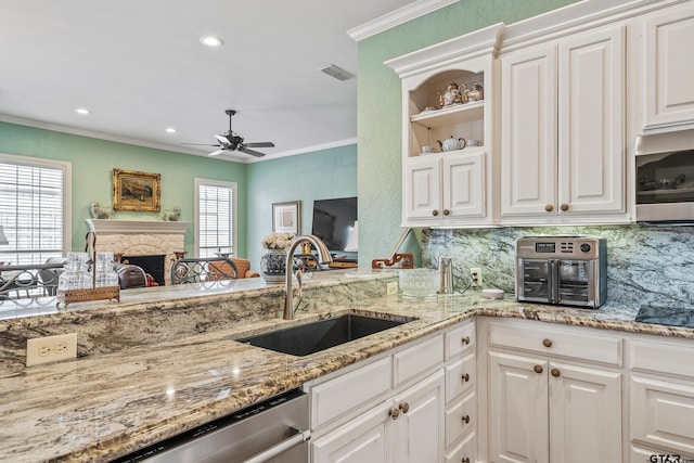 kitchen with a stone fireplace, ornamental molding, appliances with stainless steel finishes, and a sink