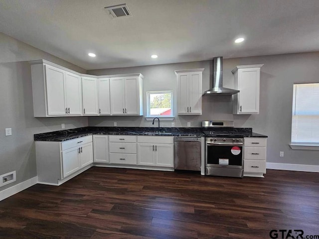 kitchen with white cabinets, appliances with stainless steel finishes, wall chimney range hood, dark hardwood / wood-style flooring, and plenty of natural light