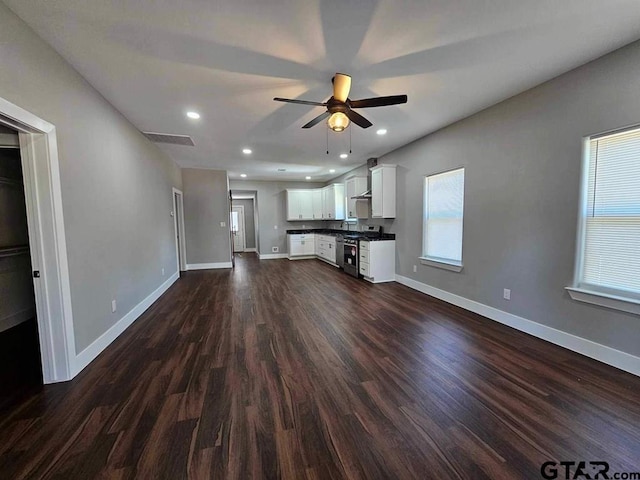 unfurnished living room with ceiling fan and dark wood-type flooring