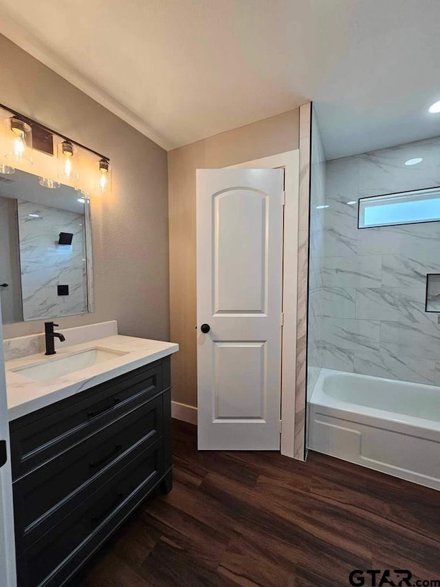 bathroom with tiled shower / bath combo, hardwood / wood-style flooring, and vanity