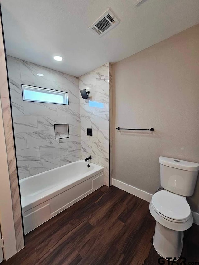 bathroom featuring toilet, hardwood / wood-style floors, and tiled shower / bath