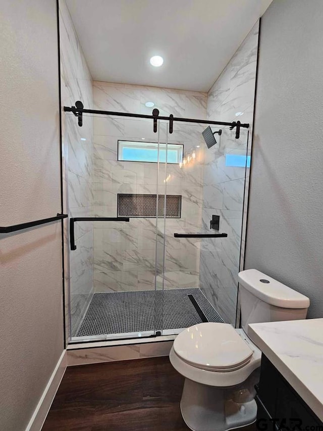 bathroom with vanity, toilet, hardwood / wood-style floors, and a shower with door