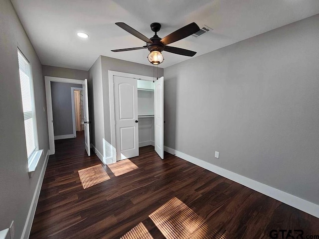 unfurnished bedroom with ceiling fan, dark hardwood / wood-style floors, and a closet