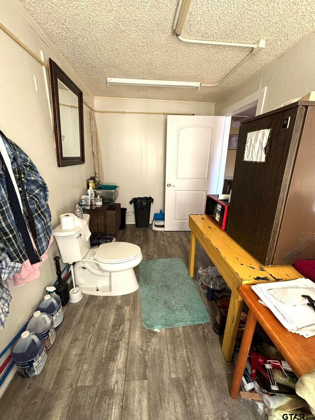 bathroom with toilet, a textured ceiling, and hardwood / wood-style flooring