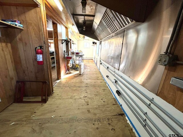 corridor featuring wood walls and vaulted ceiling