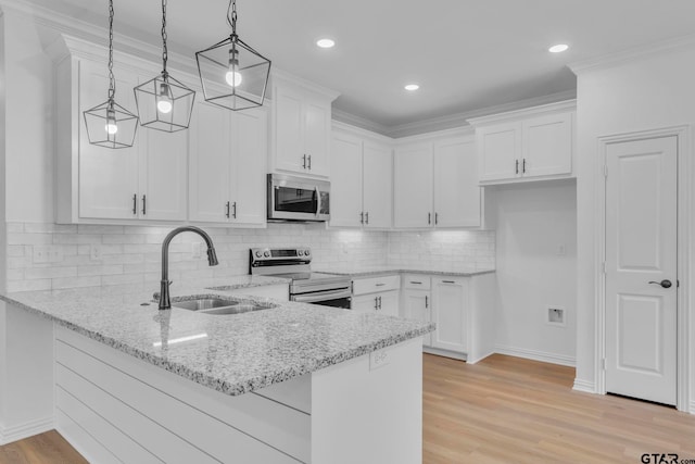 1410 W Connally St, Tyler, TX 75701 - kitchen with stainless steel appliances, a peninsula, white cabinetry, light stone counters, and decorative light fixtures