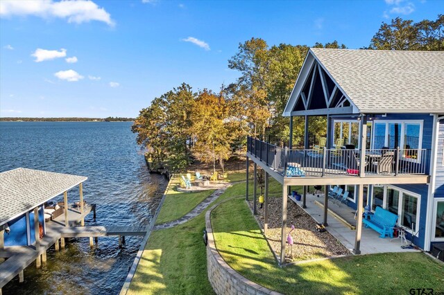 dock area featuring a lawn, a water view, boat lift, and a patio area