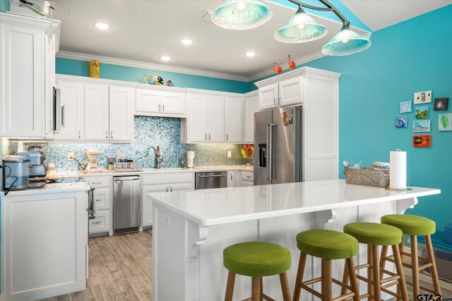 kitchen featuring a kitchen breakfast bar, backsplash, white cabinetry, light countertops, and appliances with stainless steel finishes