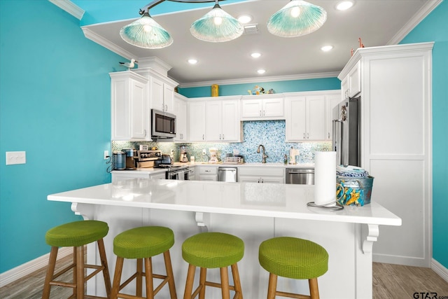 kitchen with tasteful backsplash, appliances with stainless steel finishes, a sink, baseboards, and crown molding
