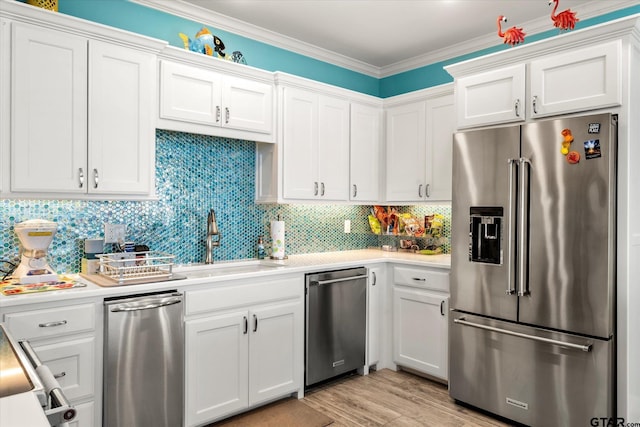 kitchen with white cabinetry, stainless steel appliances, light countertops, and a sink