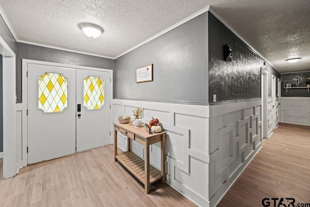 foyer entrance with crown molding, a textured ceiling, and light hardwood / wood-style flooring