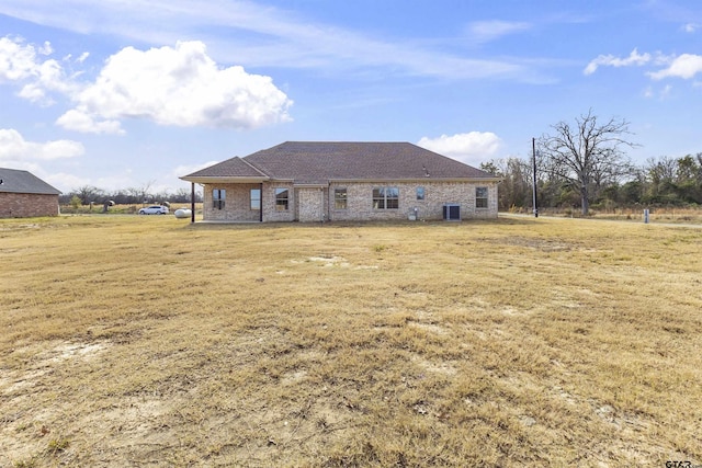 rear view of property featuring cooling unit and a lawn