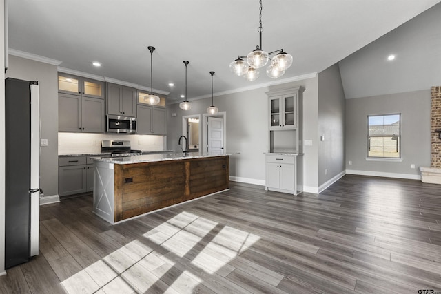 kitchen with a center island with sink, appliances with stainless steel finishes, gray cabinetry, decorative light fixtures, and light stone countertops