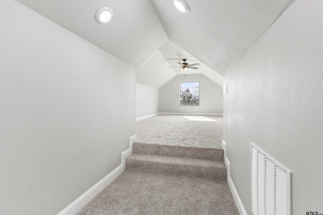 staircase featuring vaulted ceiling, ceiling fan, and carpet