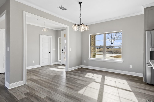 unfurnished dining area featuring wood-type flooring, crown molding, and a chandelier