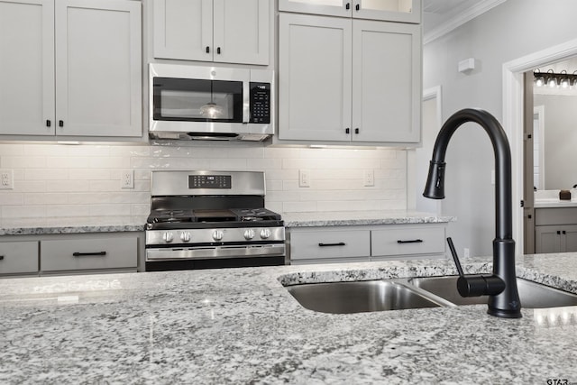 kitchen with stainless steel appliances, crown molding, white cabinetry, and sink