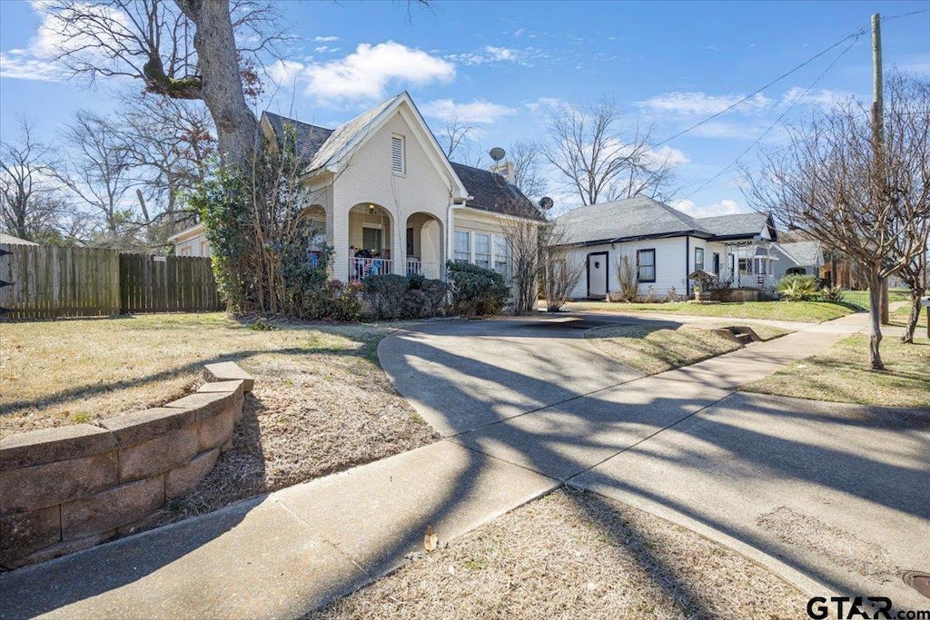 view of front of house with a front lawn, a porch, and fence