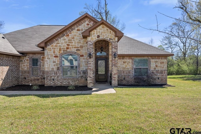 706 Duke Pl, Tyler, TX 75704 - french country style house featuring a front yard, stone siding, brick siding, and roof with shingles