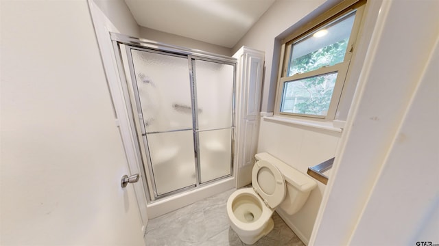 bathroom featuring a shower with shower door and toilet