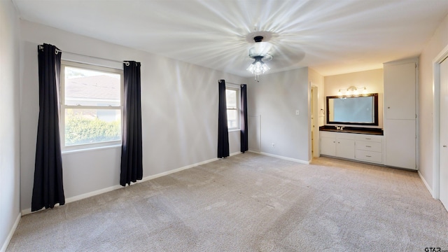 unfurnished bedroom featuring light carpet and ensuite bathroom