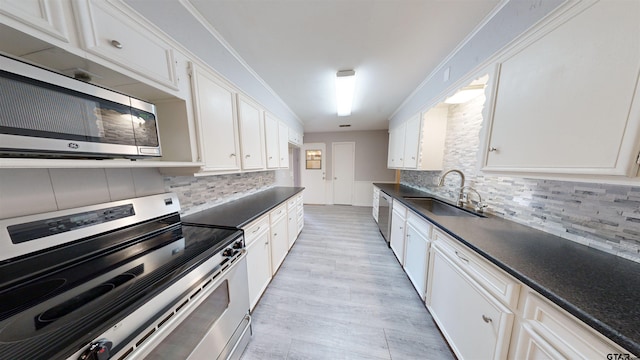 kitchen featuring stainless steel appliances, sink, decorative backsplash, and white cabinets