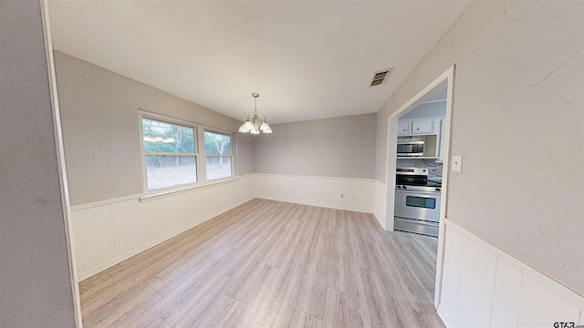 unfurnished dining area featuring an inviting chandelier and light hardwood / wood-style floors