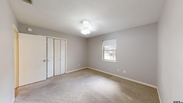 unfurnished bedroom featuring light colored carpet and a closet