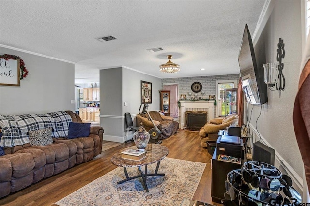 living room with a fireplace, wood finished floors, a textured ceiling, and crown molding