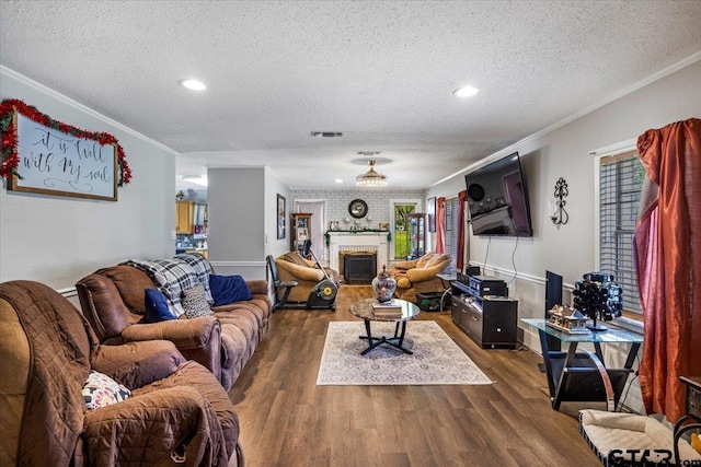 living area with ornamental molding, wood finished floors, a textured ceiling, and a fireplace