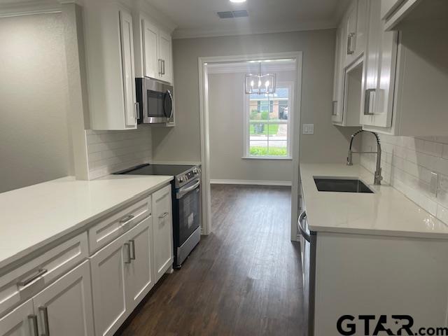110 Alpine Dr, Tyler, TX 75701 - kitchen with stainless steel appliances, backsplash, dark wood-type flooring, white cabinets, and crown molding