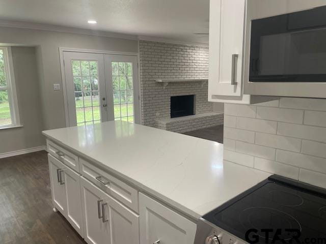 110 Alpine Dr, Tyler, TX 75701 - kitchen with decorative backsplash, range, white cabinets, crown molding, and dark wood-style flooring