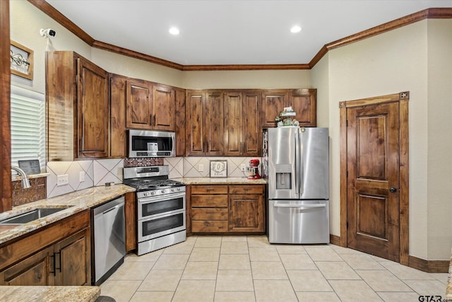 kitchen with light stone countertops, backsplash, stainless steel appliances, crown molding, and sink