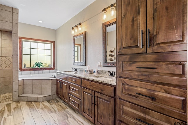 bathroom with vanity, wood-type flooring, and tiled tub