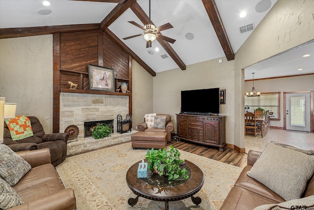 living room with high vaulted ceiling, ceiling fan with notable chandelier, a stone fireplace, hardwood / wood-style flooring, and beamed ceiling