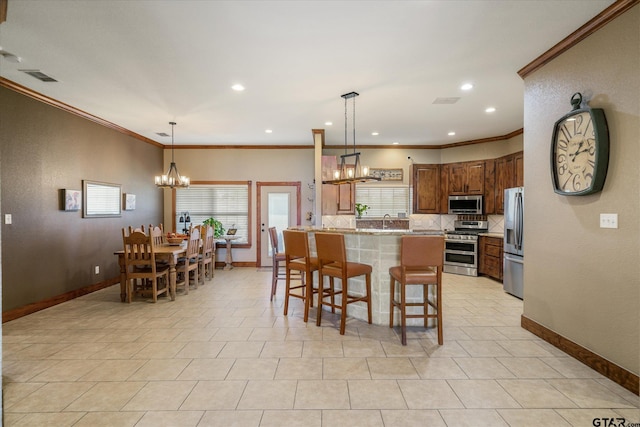 kitchen with a chandelier, ornamental molding, decorative light fixtures, and appliances with stainless steel finishes