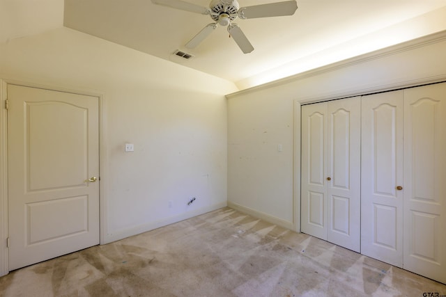 unfurnished bedroom featuring ceiling fan, light colored carpet, lofted ceiling, and a closet