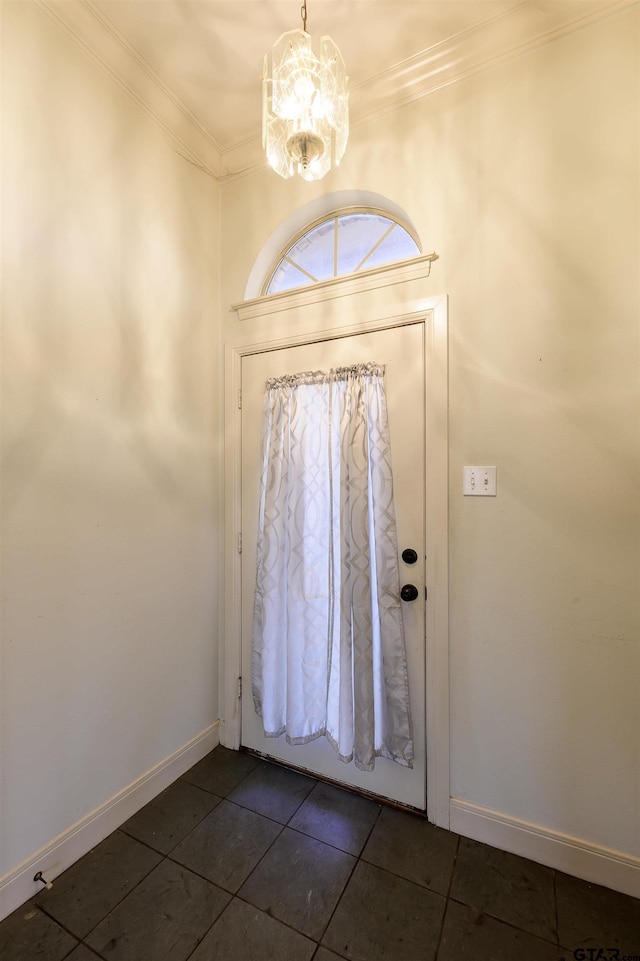 foyer entrance with crown molding, a chandelier, and dark tile patterned flooring