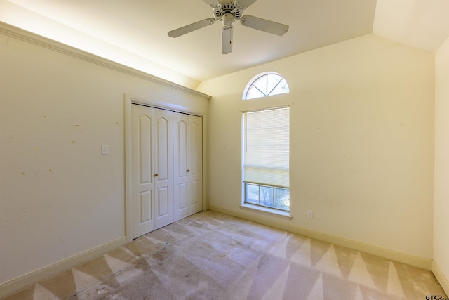 unfurnished bedroom with ceiling fan, a closet, light colored carpet, and lofted ceiling