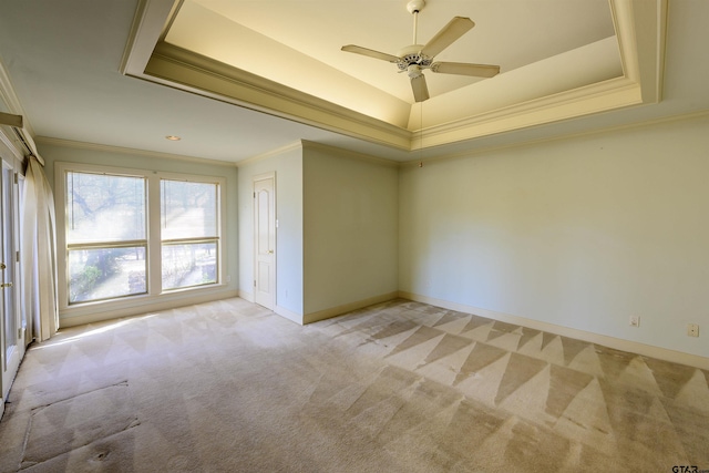 carpeted spare room featuring a tray ceiling, ceiling fan, and crown molding