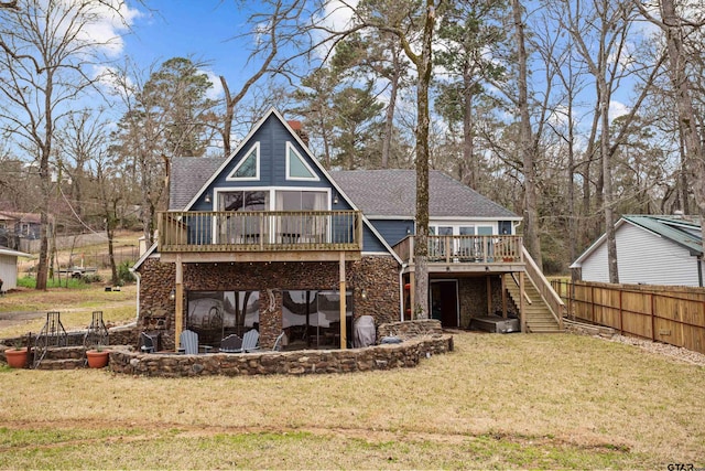 back of house featuring fence, roof with shingles, a wooden deck, stairs, and a lawn