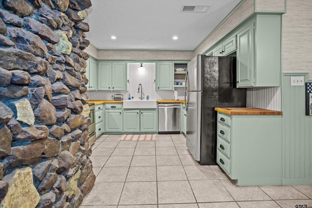 kitchen with green cabinetry, stainless steel appliances, visible vents, and a sink