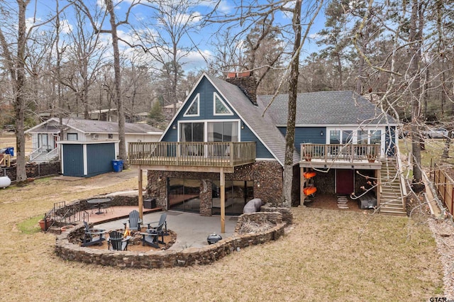 back of house featuring stairway, a wooden deck, an outdoor fire pit, a patio area, and a lawn